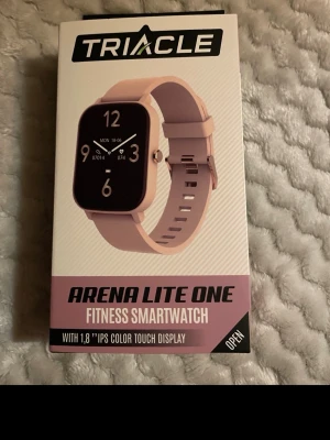 Triacle Arena Lite One smartklocka rosa - Triacle Arena Lite One är en smartklocka med 1,8-tums färgskärm och rosa silikonarmband. Klockan har pulsmätare, stegräknare, sömnanalys, notiser, flera sportlägen och är IP67-vattentålig. Perfekt för dig som vill ha koll på träning och hälsa direkt på handleden.