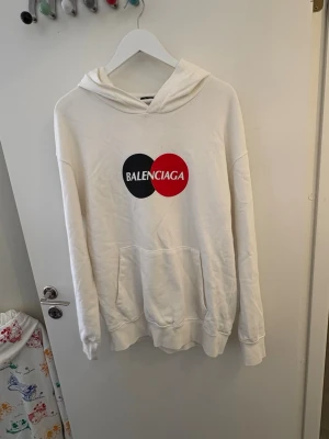 Vit Balenciaga t-shirt med tryck - Vit t-shirt från Balenciaga med stort grafiskt tryck i svart och rött , är i ett väldigt fint skick säljes då den inte passar mig längre, storlek L
