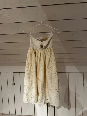 Ljus ärmlös klänning med broderi - Söt ljus kortklänning med broderade detaljer och hålmönster.  Den är offshoulder och snygg sommar/strand klänning.