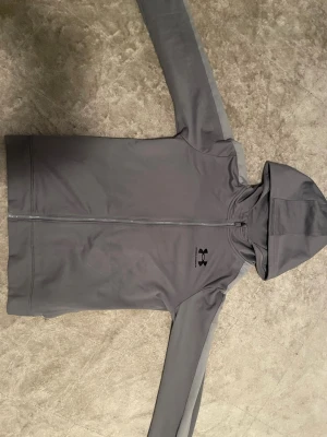 Grå Under Armour zip up - Grå under armour tröja som jag precis köpte från en annan säljare på plick. Tröjan var för liten på mig men annars ser tröjan ser jättebra ut, jag ville verkligen ha den men den passa ej.