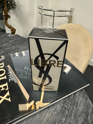 Yves Saint Laurent Libre parfym - Säljer en lyxig parfym från Yves Saint Laurent, Libre. Förpackningen är elegant i svart och guld med stora YSL-bokstäver och stilren design. Perfekt för dig som gillar exklusiva dofter och snygg förpackning.