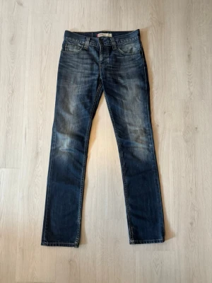 Levi’s Jeans | 511 - Snygga mörkblå jeans från Levi's med klassisk femficksdesign och raka ben. Jeansen har slitningar och en cool tvätt som ger en avslappnad vibe. Perfekta till sneakers eller boots för en trendig look. Tyvärr har lappen med storleken slitits bort, uppskattning på storlek är 29/32