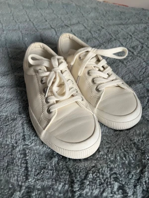 Vita låga sneakers i skinnimitation - Stilrena vita sneakers från polo ralph lauren  med lågt skaft och klassisk design. Skorna har vita snören, silverfärgade öljetter och ovandel Perfekt .