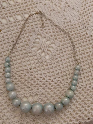 Halsband med ljusblå pärlor - Snyggt halsband med stora och små ljusblå pärlor på en tunn silverfärgad kedja. Pärlorna har en glansig yta och är placerade i en gradvis storleksordning. Perfekt accessoar för att lyfta din outfit.