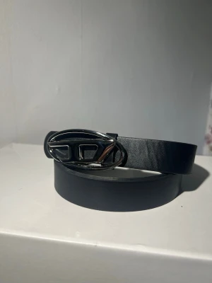 Vintage diesel Belt  - Stilrent svart skärp med ett ovalt metallspänne i silverfärg. Skärpet har en slät yta och passar perfekt till jeans eller kostymbyxor. Enkel design som ger en snygg touch till din outfit.
