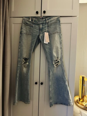Ljusblå lågmidjade bootcut jeans med slitningar - Säljer ett par ljusblå lågmidjade bootcut jeans från ginatricot. Helt oanvända med prislapp kvar. 14 + Young storlek L
