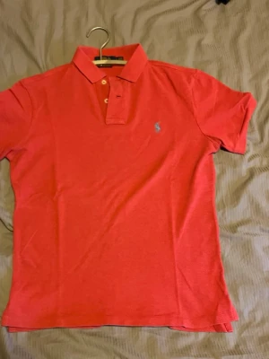 Röd pikétröja från Ralph Lauren - Säljer en helt ny och äkta piké från Polo Ralph Lauren i en snygg röd färg. Perfekt för sommaren – stilren, bekväm och lätt att matcha med både shorts och jeans.  Storlek: S Skick: Helt ny (oanvänd) Nypris: 1095 kr Pris: 249 kr (kan diskuteras vid snabb affär)  Passa på att fynda en klassisk piké i toppskick till ett bättre pris. Hör av dig vid intresse eller frågor.