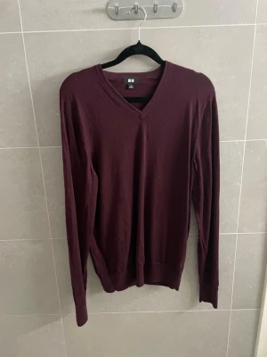 Vinröd V neck 100% merino tröja Uniqlo - Helt ny, har bara legat i garderoben i ett år! skrivas ifall bra bilder krävs. Lite skrinkliga o så men det försvinner i tvätten eller om du ska strika dom eller hur du än gör. Vinröd stickad tröja från Uniqlo med V-ringning och långa ärmar. Tröjan har en enkel och stilren design med ribbade muddar vid ärmslut och nederkant. Perfekt för lager-på-lager och passar till många olika outfits. 