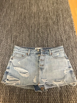 Ljusa jeansshorts från Zara - Snygga ljusblå jeansshorts från Zara med slitna detaljer och råa kanter. Klassisk femficksmodell med knappar framtill och bälteshällor. Perfekta för en avslappnad och trendig look.