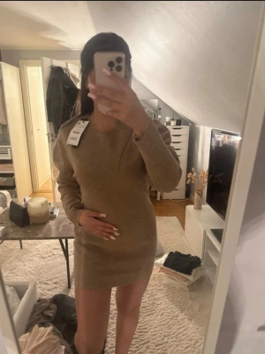 Beige stickad kortklänning Zara - Säljer en beige stickad kortklänning från Zara. Klänningen har lång ärm, rund halsringning och en enkel, rak passform. Perfekt att styla med boots eller sneakers för en trendig look. Den har en liten dragkedja i nacken så det är lättare att få in huvudet. Aldrig använd, köpt för 859 kr. Den är i storlek M men passar en storlek S lika bra.