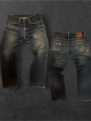 Sinnessjuka Levi's med fet tvätt (straight fit) - Säljer ett par blå Levi's jeans med snyggt slitna detaljer och klassisk femficksmodell. Jeansen har raka ben, tydliga slitningar på fram- och baksida samt en patch i läder baktill. Perfekta för en avslappnad streetstil. Har ett stort slitning vid knät ställ frågor! Inga returer