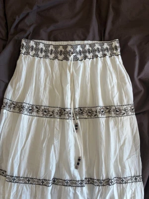 Långkjol från Zara - Vit långkjol med svarta broderade mönster och snörning i midjan. Jättefin och perfekt till sommaren.
