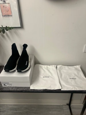 Balenciaga Speed Trainer svarta sneakers - Säljer ett par svarta Balenciaga Speed Trainer sneakers med vit sula och stickad strumpliknande ovandel. Ikonisk logga på sidan och superbekväm passform. Kommer med originalkartong och två dustbags. Perfekta för dig som gillar streetwear och stilren design.