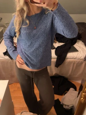 Blå stickad tröja i boxy modell - Mysig blå stickad tröja med rund hals och avslappnad, boxy passform. Tröjan har långa ärmar och en enkel, stilren design som passar perfekt till jeans eller mjukisbyxor. Perfekt för dig som gillar en chill och trendig look.
