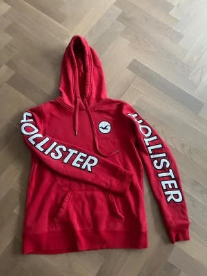 Röd hoodie från Hollister - Ascool Hollister hoodie med unika tryck. Tröjan är strl M och skick ca 8/10. Inga defekt. Ruggigt fräna ärmar och bra design på bröstet. 