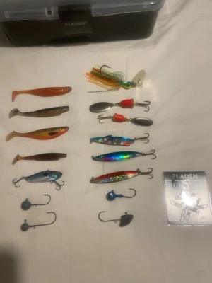 Fiskedrag och tillbehör med beteslåda - Säljer ett set med fiskedrag, jiggar, spinnare och skeddrag i olika färger samt tillbehör som jigghuvuden och beteslås. Allt kommer med en svart plastlåda från Fladen med transparent lock och fack för enkel förvaring. Perfekt för dig som gillar fiske och vill ha variation i betesval.