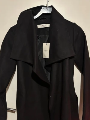 Svart Lång Kappa - helt ny & oanvänd, kan finnas lite hundhår på den då den legat i en flyttkartong.