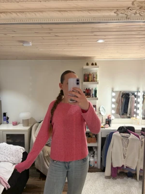 Rosa stickad tröja med rund hals - Mysig rosa stickad tröja med rund halsringning och långa ärmar. Tröjan har ribbstickade muddar vid ärmslut och nederkant. Perfekt för att hålla värmen under kyliga dagar.