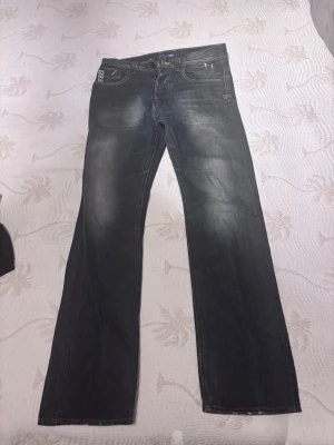 Mörkblåa G-Star RAW jeans med raka ben - Säljer ett par mörkblåa jeans från G-Star RAW med raka ben och diskret slitning framtill. Klassisk femficksmodell med logga på bakfickan och vid linningen. Jeansen är tillverkade i bomull och har en cool, avslappnad look.