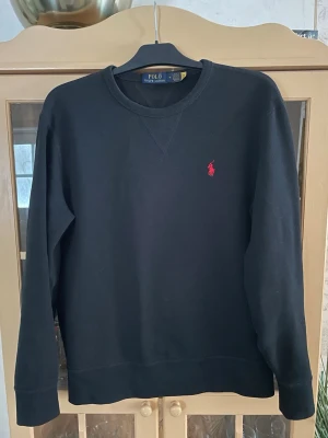Svart sweatshirt från Polo Ralph Lauren - Svart sweatshirt från Ralph Lauren i storlek M. Endast använd några gånger och syns inte på plagget. Perfekt för en stilren och enkel look.