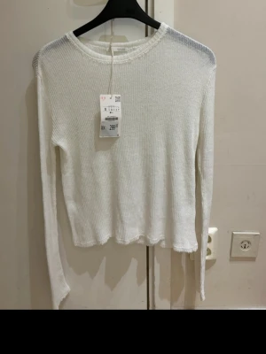  Ny Vit tunn  ribbstickad tröja från Zara  - Säljer en vit ribbstickad tröja från H&M med rund halsringning och långa ärmar. Tröjan har en enkel, clean look och är lätt croppad i modellen. Perfekt att styla med jeans eller kjol för en fräsch vardagsoutfit.