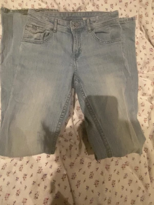 Ljusblå bootcut jeans med fickdetaljer - Ljusblå utsvängda jeans med jättesnygga knappfickor från H&M i strl 170! Dem har ett speciellt material men de tycker jag gör de bättre! perfekt för en basic outfit! kontakta för fler bilder eller info🩷
