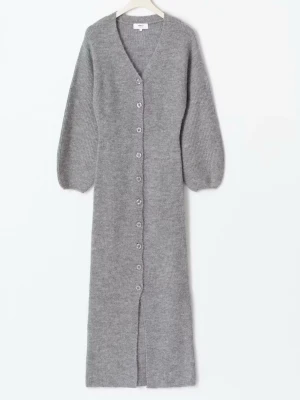 Lång grå stickad kofta med knappar - Lång, mjuk och stickad kofta i grått med v-ringning och stora ballongärmar. Koftan har knappar hela vägen framtill och är perfekt för lager på lager. Materialet ser ut att vara ullmix för extra värme och komfort.