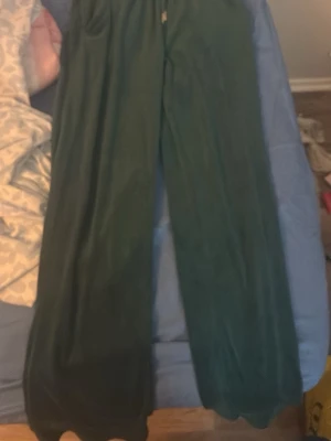 Mörkgröna mjukisbyxor med fickor - Säljer ett par mörkgröna mjukisbyxor med breda ben och resår i midjan. Byxorna har två stora fickor fram och är gjorda i ett mjukt, skönt material som passar perfekt för chill dagar. Perfekta för dig som gillar avslappnad stil.