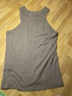 Beige ribbad linnetopp - Säljer en enkel och stilren beige linnetopp med ribbad struktur. Toppen är ärmlös och har en klassisk rund halsringning. Perfekt att matcha med jeans eller kjol för en avslappnad look.