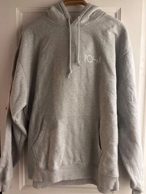 Grå hoodie från Polar Skate Co - Säljer en grå hoodie från Polar Skate Co med vit logga på bröstet och en stor grafisk cirkel i gult, grönt och vitt på ryggen. Klassisk känguruficka och dragsko i huvan. Perfekt för dig som gillar streetwear och skön stil.