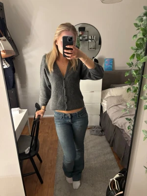 Blå bootcut jeans med låg midja - Säljer ett par blå bootcut jeans med låg midja och klassisk femficksdesign. Jeansen har en lätt tvättad look och sitter tajt över höfterna och låren för att sedan bli vidare nedtill. Perfekta för en avslappnad och trendig stil.