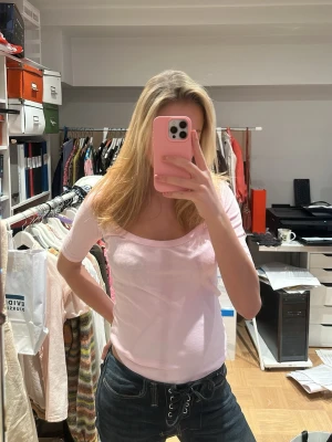 Ljusrosa topp med kort ärm - Snygg ljusrosa topp med rundad halsringning och korta ärmar. Modellen är figurnära och passar perfekt till jeans eller kjol. Säljer pga av at tiden är för stor