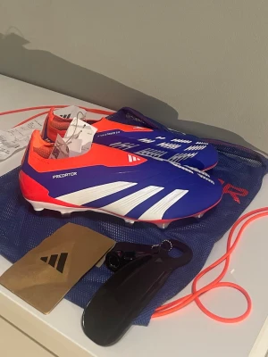 Adidas Predator Elite fotbollsskor - Helt nya Adidas Predator Elite Laceless SG i storlek 44. Aldrig använda.  Kvitto finns. Skobag medföljer, samt skohorn, extra dubbar och dubbnyckel. SG-dobbar för spel på mjukt/gräsunderlag. Köpta på Adidas i England.  Skickar så fort jag kan efter köp.