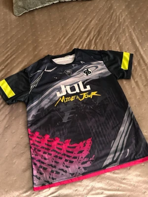 Svart grafisk t-shirt JuL - Cool svart t-shirt från Mise à Jour med grafiskt tryck, JuL, vitt, gult och rött. T-shirten har korta ärmar med gula detaljer och är gjord i ett lätt och sportigt polyestermaterial. Perfekt för dig som gillar streetwear och unika prints. Står storlek xxl men sitter som M/L🤗