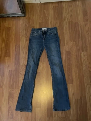 Low waist bootcut jeans - Snygga blå bootcut jeans från Zara med klassisk femficksmodell och låg midja. Jeansen har en lätt tvättad look och är tillverkade i mjukt denimtyg som ger en bekväm passform. Perfekta för en avslappnad och trendig stil. Storlek 34