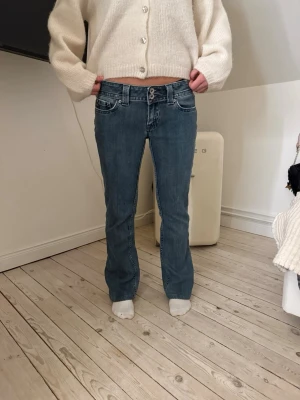Blå bootcut jeans från Sweet - Snygga blå bootcut jeans från miss me med låg midja och dem är väldigt vintage . Jeansen har dekorativa sömmar och broderad logga på bakfickan. Perfekta för en avslappnad och trendig look.Tyvärr som man ser på bilden så har lite rött nagellack spillts på ena benet men det syns inte . Jag kan tyvärr inte ha dessa eftersom jag har växt ur dem 