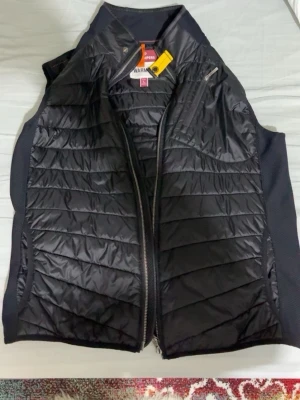 Svart dunväst från Parajumpers - Snygg svart dunväst från Parajumpers med quiltad framsida och baksida, dragkedja framtill och praktiska fickor med dragkedja. Västen har en sportig look och är tillverkad i lätt, glansigt material med diskret logga i nacken.