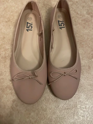 Ljusa rosa ballerinaskor med rosett - Säljer ett par ljusrosa ballerinaskor från 157 i storlek 37. Skorna har en klassisk rund tå och en söt liten rosett framtill. Tillverkade i ett slätt syntetmaterial med mjuk innersula för extra komfort. Perfekta för dig som gillar enkel och stilren design.