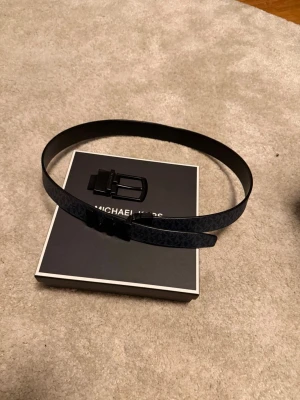 Michael kors bälte - Fint Michael kors bälte som går att använda med blått MK hologram eller helt svart Sam ingår det två fästningar, ett klassiskt och ett med MK. Längd 110 cm