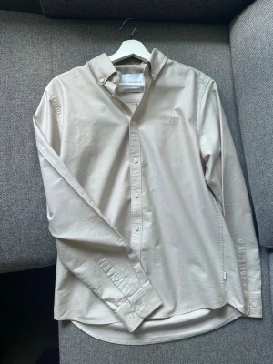 Les Deux Oxfordskjorta (beige)   - Hej! Säljer denna mycket fina oxfordskjorta från Les Deux. Köptes helt ny men var tyvärr lite för stor. Den är därför i princip rent nyskick och har inte använts. Nypriset ligger på ungefär 1100 kr. 