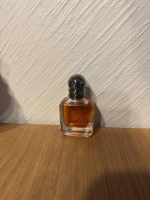 Elegant parfymflaska med silverkula - Snygg parfymflaska i genomskinligt glas med fyrkantig form och rund silverfärgad kork. Innehållet är bärnstensfärgat och flaskan har en stilren design som passar perfekt på sminkbordet.