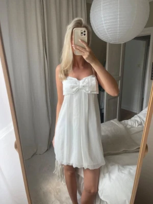 Supersöt klänning med rosett - Säljer denna vita klänning me rosett ifrån Gina Tricot! Storlek M men passar bra på mig som brukar ha S! Det går att justera längden på banden!