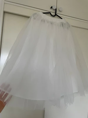 Vit tyllkjol med volym - Säljer en fluffig vit tyllkjol med flera lager som ger extra volym. Kjolen har resår i midjan och är perfekt för dig som vill ha en lekfull och luftig look. Passar till många olika stilar och är superfin att styla med både sneakers och klackar. Storlek S