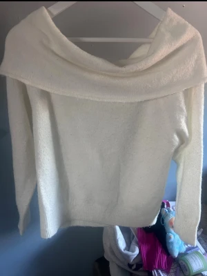 Vit off shoulder stickad tröja - Säljer en vit stickad tröja med bred off shoulder-krage. Tröjan har lång ärm och är gjord i ett mjukt, mysigt material som passar perfekt till kyligare dagar. Enkel och stilren design som är lätt att matcha med olika outfits.