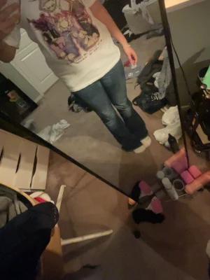 Vit t-shirt med animeinspirerat tryck - Säljer en vit t-shirt med färgglatt animeinspirerat tryck på framsidan och texten 'Better to light one candle than to curse the monsters'. T-shirten har normal passform och korta ärmar. Perfekt för dig som gillar coola och unika motiv!