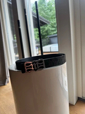 Demont D belt - Säljer ett Demont bälte som är reversible där du kan använda ena sidan med monogram eller andra sidan som är helt svart.  Inte använt speciellt mycket, storlek 100cm