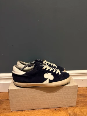 Mörkblå sneakers från The gallerist  - Snygga mörkblåa the gallerist skor, skorna är i väldigt bra skick och har endast lite slitage i nedre hörnet av hälen på båda skorna( inget man märker av) strlk 44 passar även en storlek upp och ner. Ny pris 2500. Om ni har några frågor skriv!