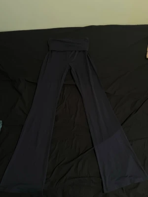 Marinblåa utsvängda leggings - Säljer ett par marinblåa leggings med utsvängda ben, den har bred linning upptill som kan vikas ner för extra komfort och en lite mer lågmidjad look. Perfekta för en trendig och avslappnad stil. Materialet känns mjukt och stretchigt.