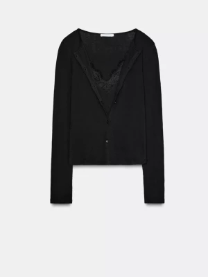 Svart cardigan med spetsdetalj - Stilren svart cardigan med långa ärmar och knäppning framtill. Tröjan har en snygg spetskant vid urringningen som ger en extra touch. Perfekt att matcha med jeans eller kjol för en trendig look.