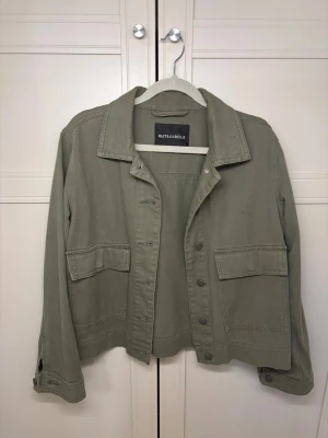 Olivgrön jeansjacka från Rut&Circle - Stilren olivgrön jeansjacka från Rut&Circle med krage, Jackan har knappar vid ärmslut och en skön kvalitet! (Pris kan diskuteras)